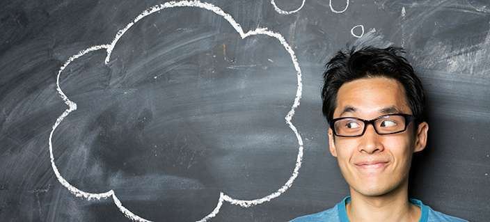 Chinese man standing next to thought bubble drawn on chalkboard.