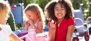 Elementary Pupils Sitting At Table Eating Lunch